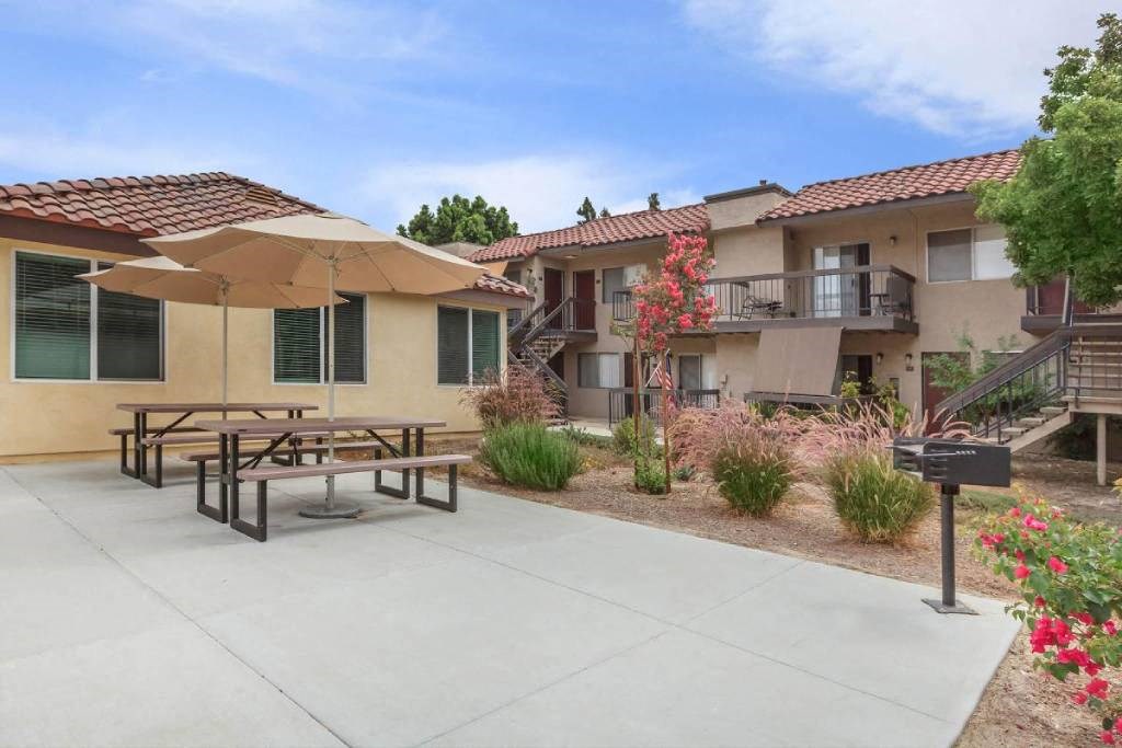a patio with a picnic table in front of an apartment building