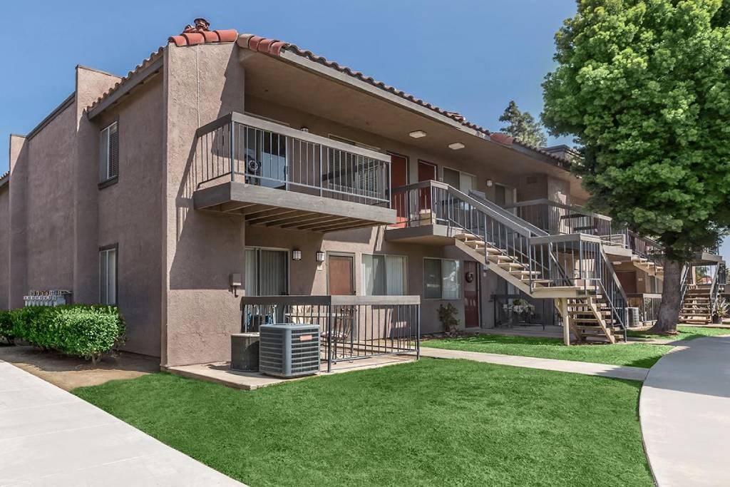an apartment building with stairs and a grass yard