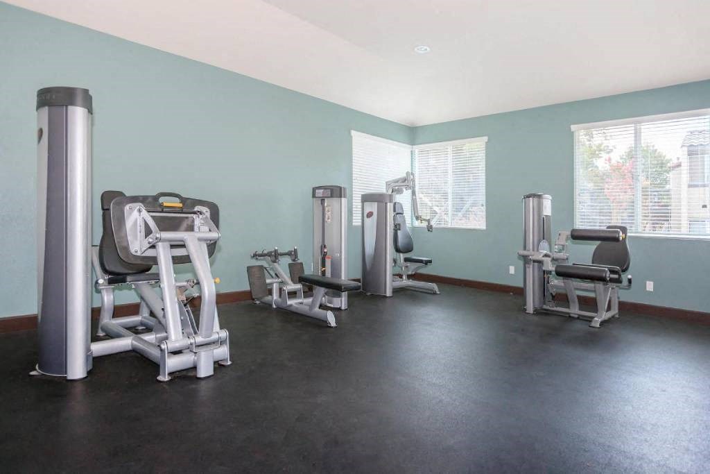 a gym with various exercise equipment in a room with windows