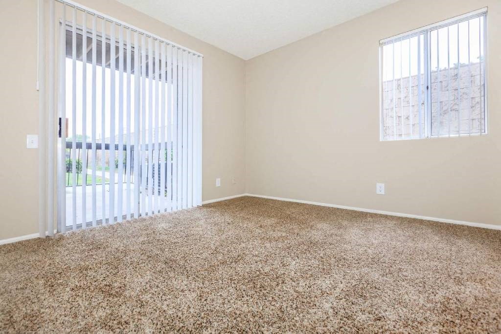 an empty living room with a large window and carpet