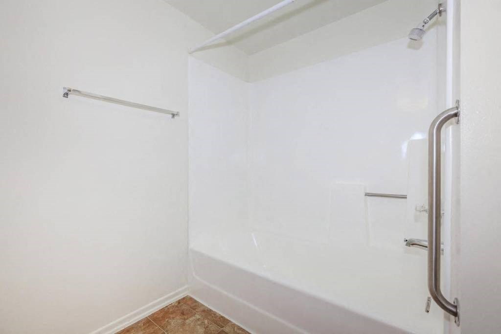 a white bathroom with a shower and a towel rack