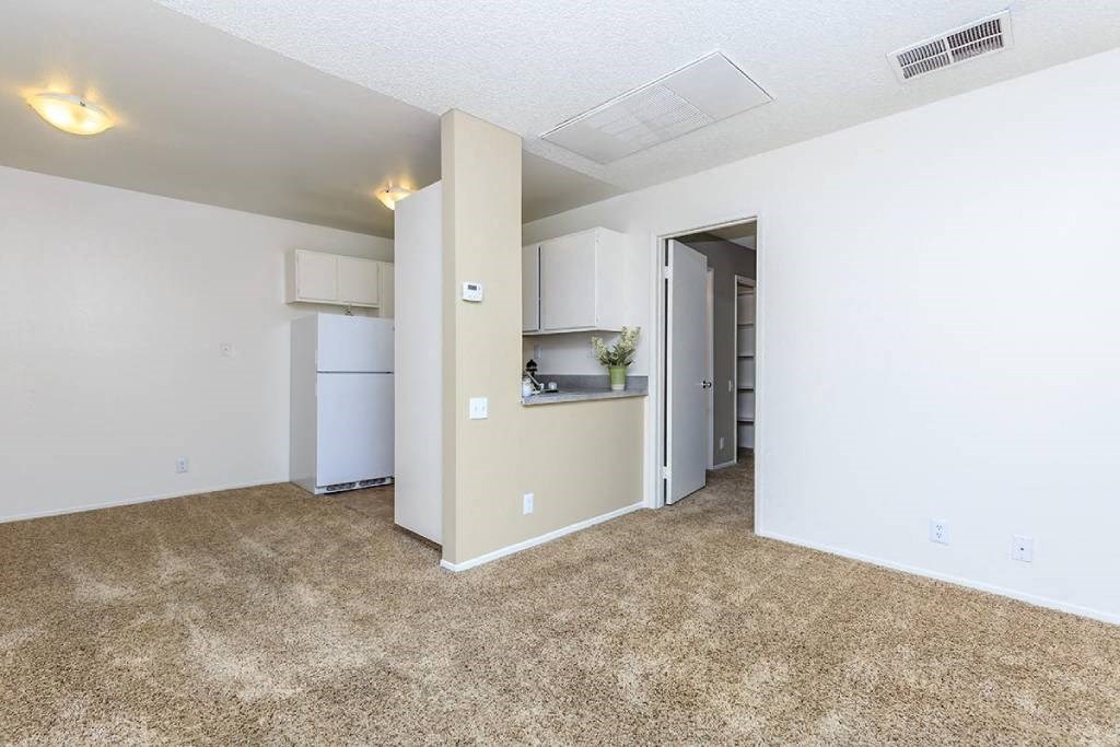 the living room and kitchen of an apartment with white walls