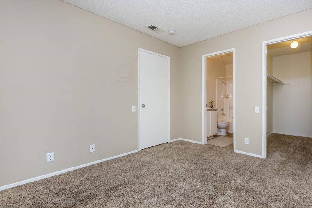 an empty living room with an open door to a bathroom
