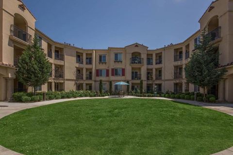 an exterior view of an apartment building with a green lawn