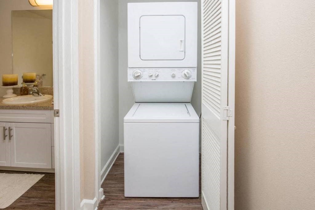 a white washer and dryer in a bathroom with a sink