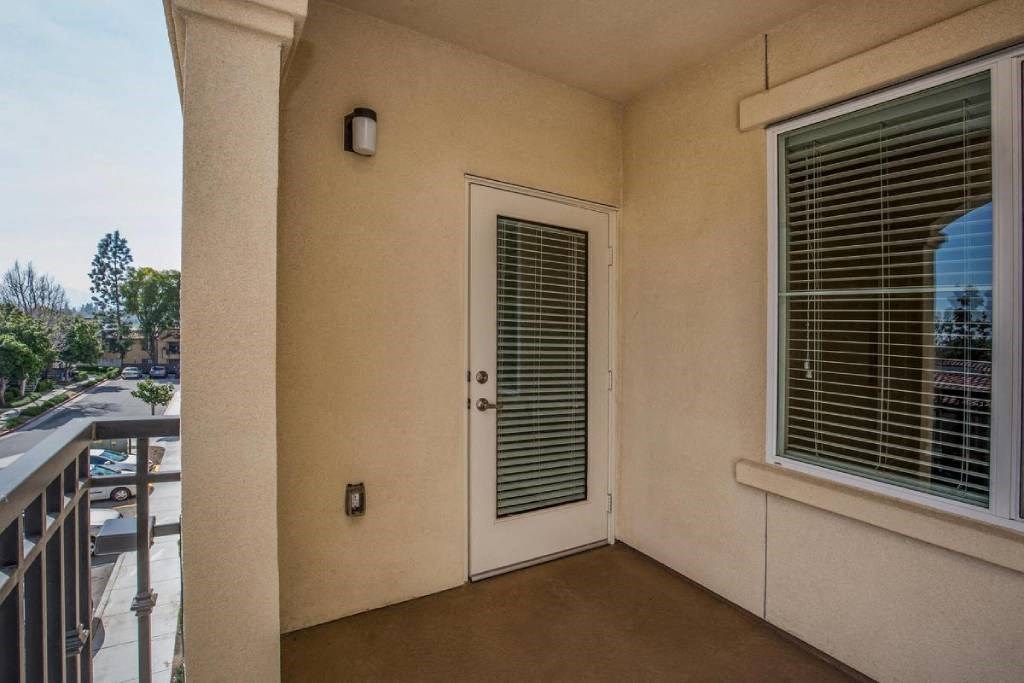a balcony with a door and a window with blinds on it