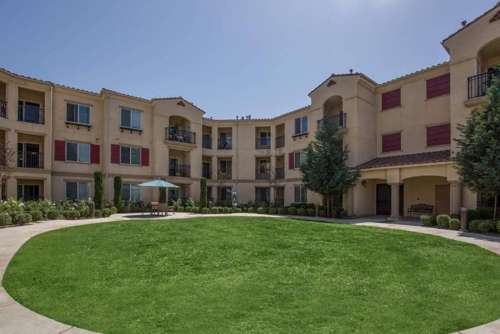 an outside view of an apartment building with a green lawn