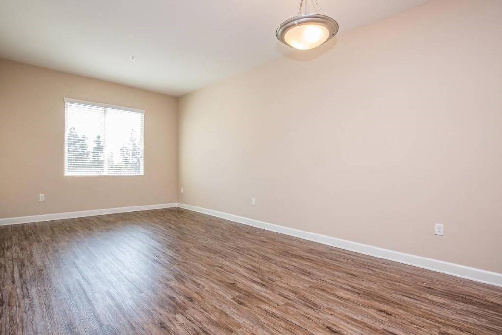an empty living room with wood floors and a window