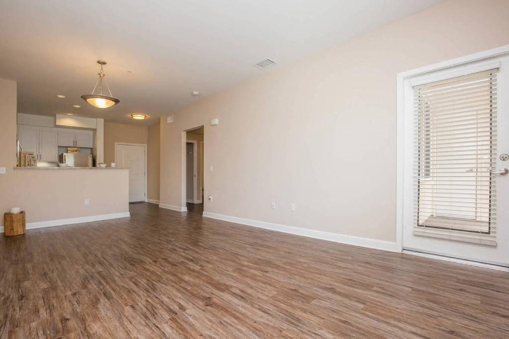 the living room and kitchen of an empty house with a wood floor