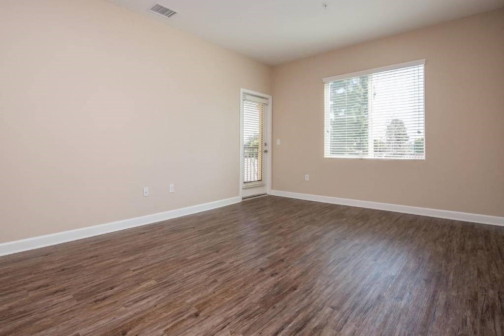 an empty living room with wood flooring and a window