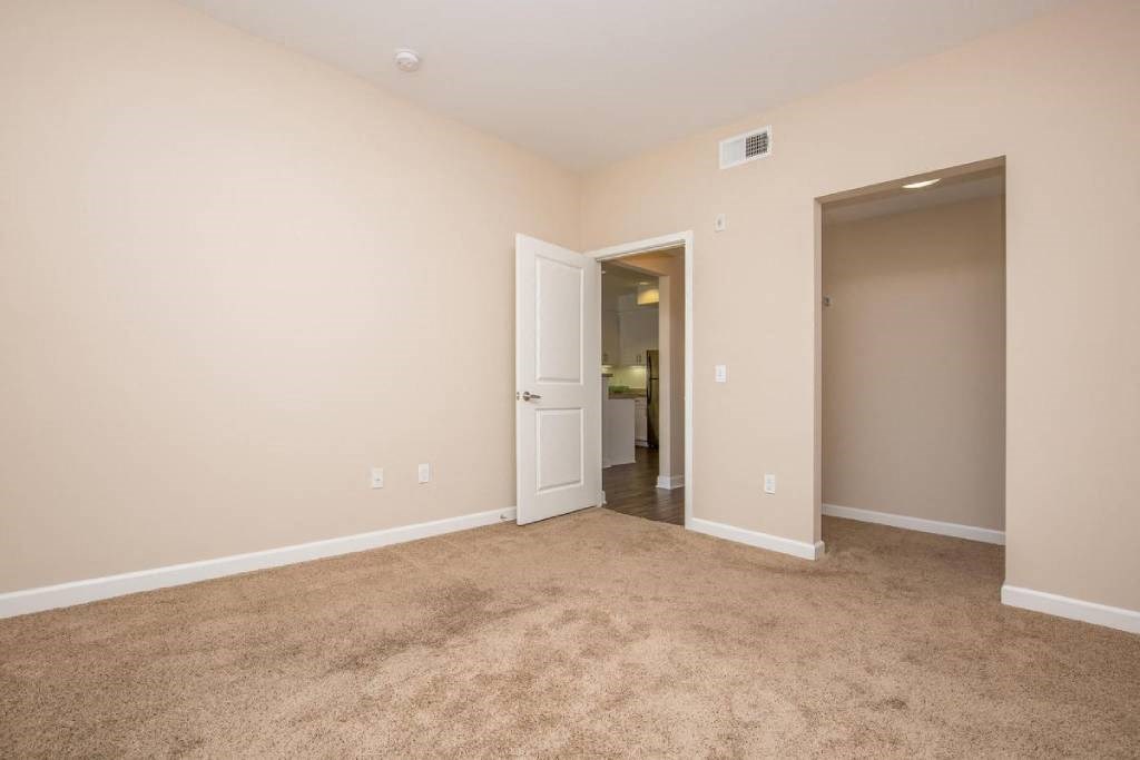 a living room with carpet and a door to a bathroom