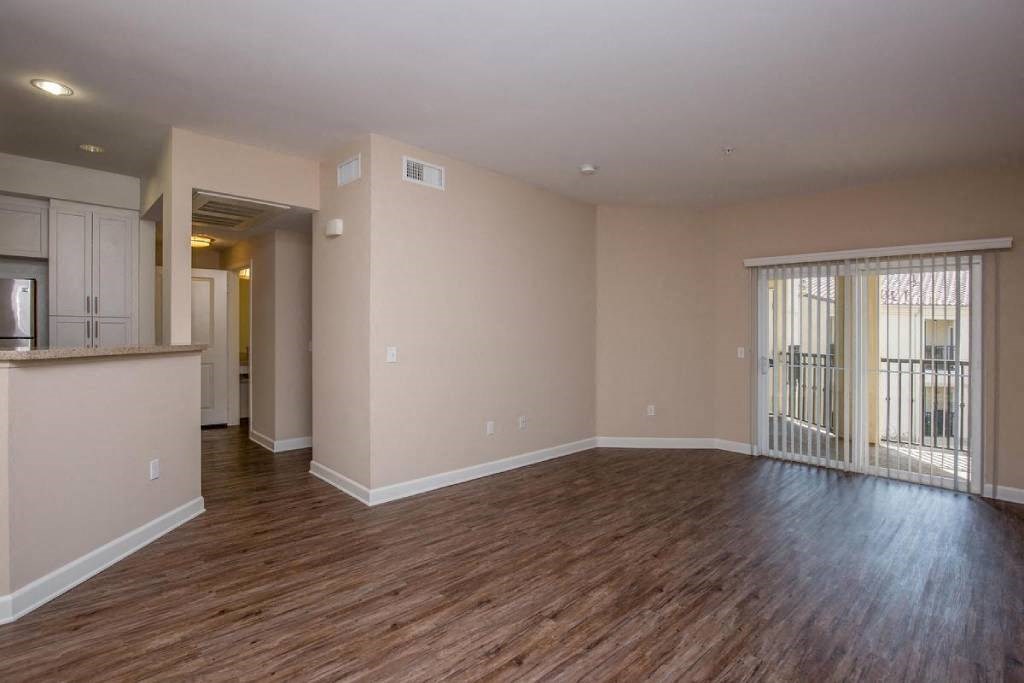 an empty living room with wood flooring and a window