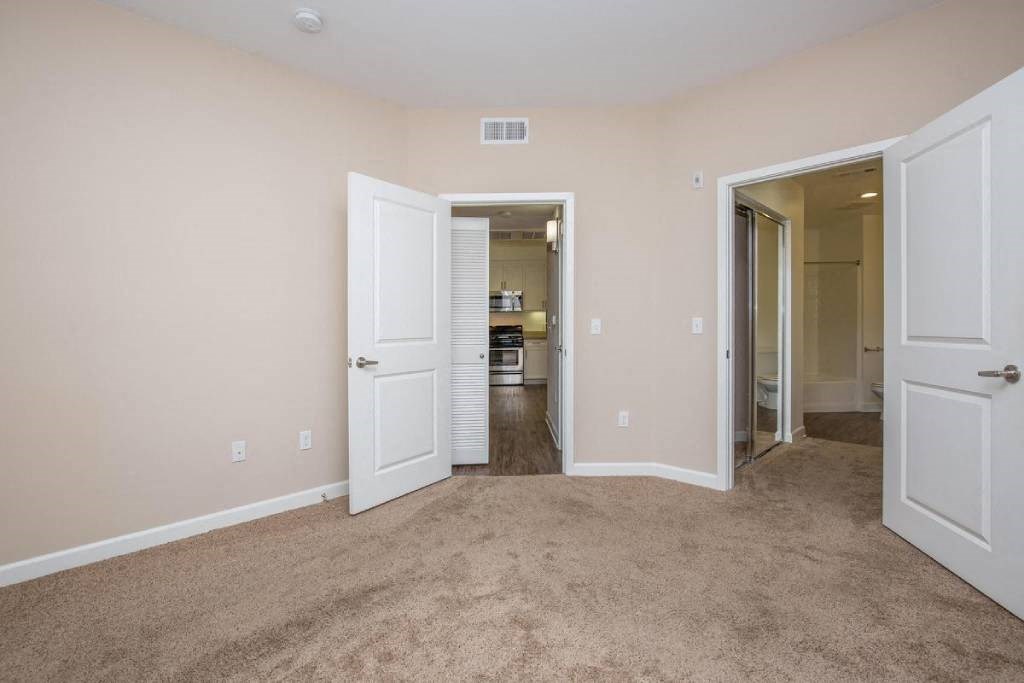 a bedroom with two doors and a hallway to a kitchen