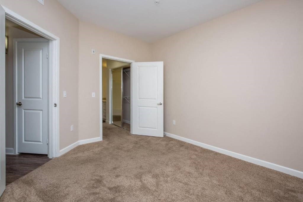 a bedroom with a carpeted floor and a door to a closet