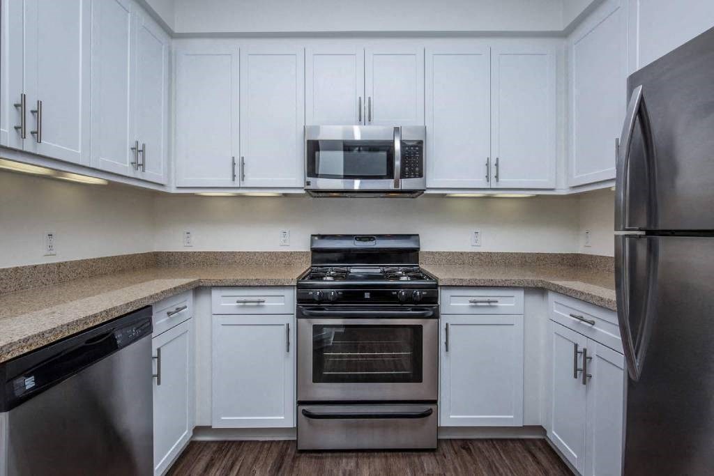 a kitchen with white cabinets and stainless steel appliances