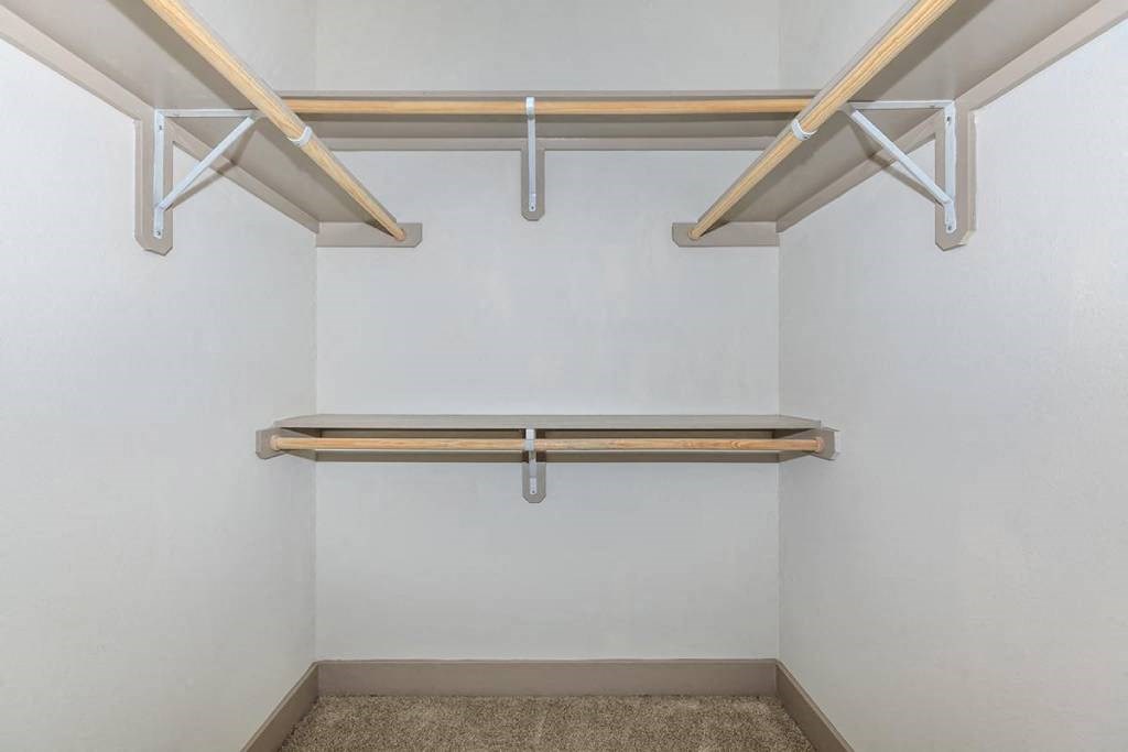 a walk in closet with shelves and a white wall