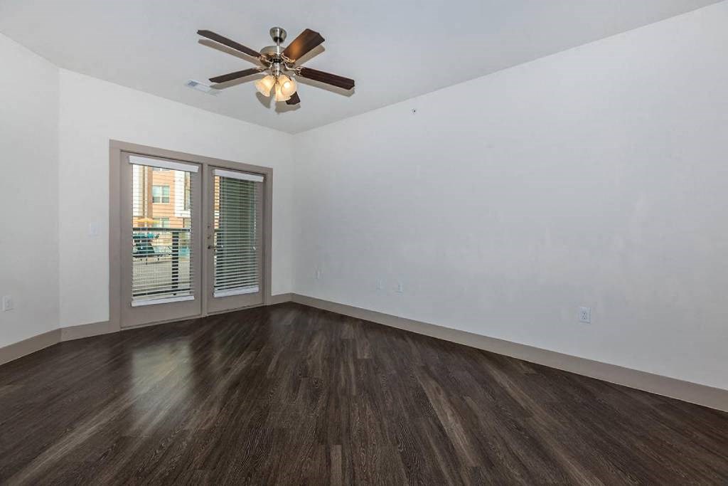 an empty living room with a ceiling fan and a window