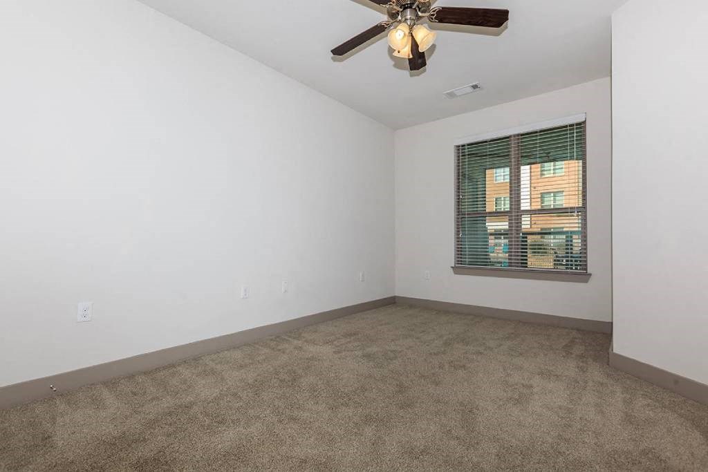 an empty living room with a ceiling fan and a window