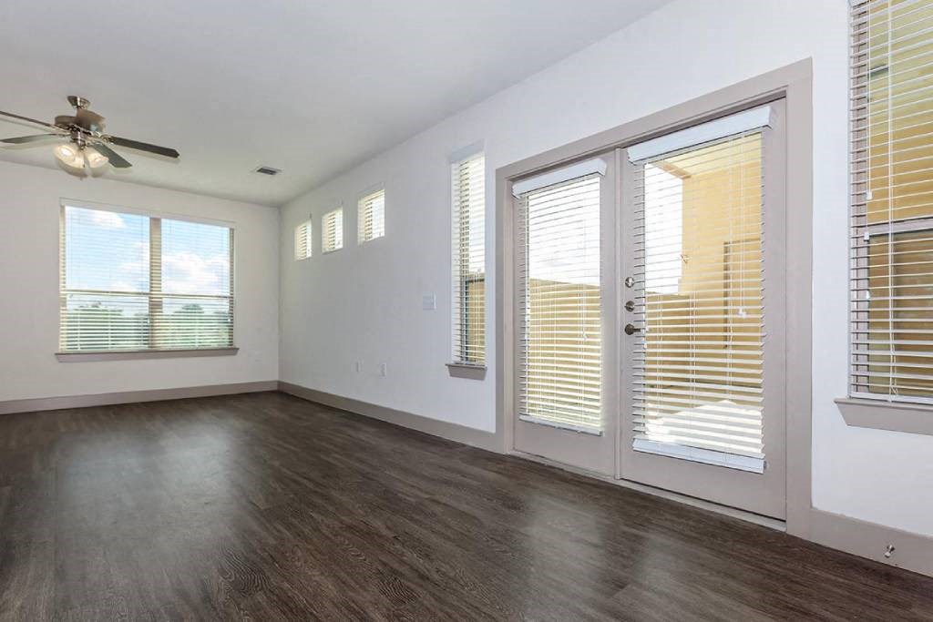 an empty living room with windows and a ceiling fan