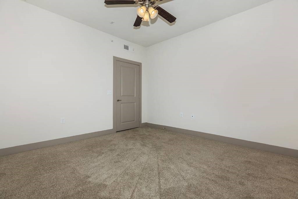 an empty living room with a ceiling fan