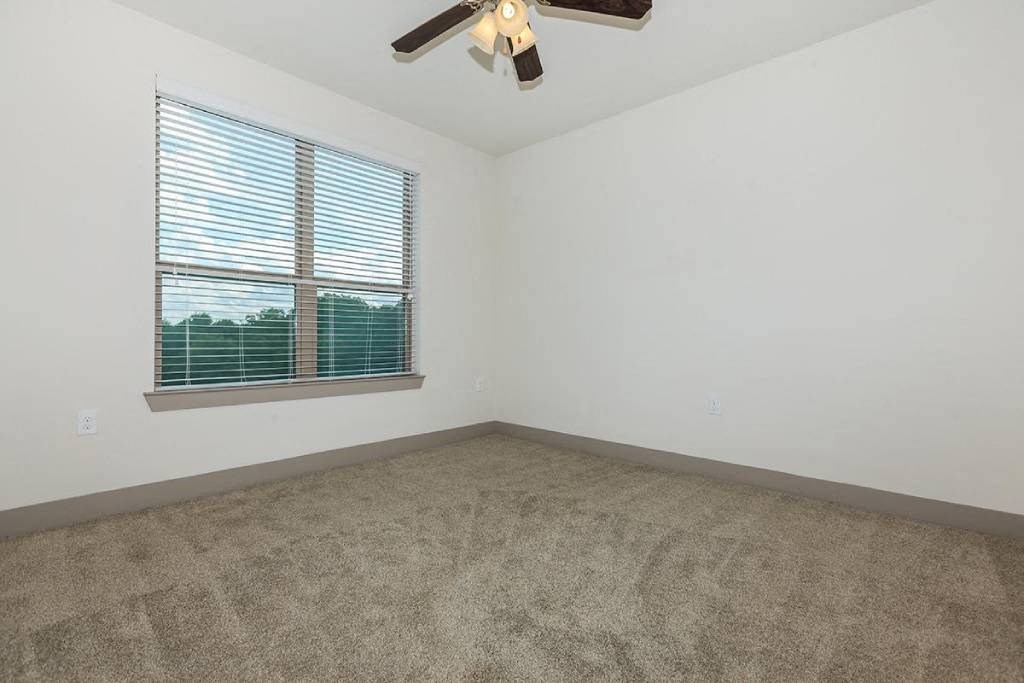an empty room with a window and a ceiling fan