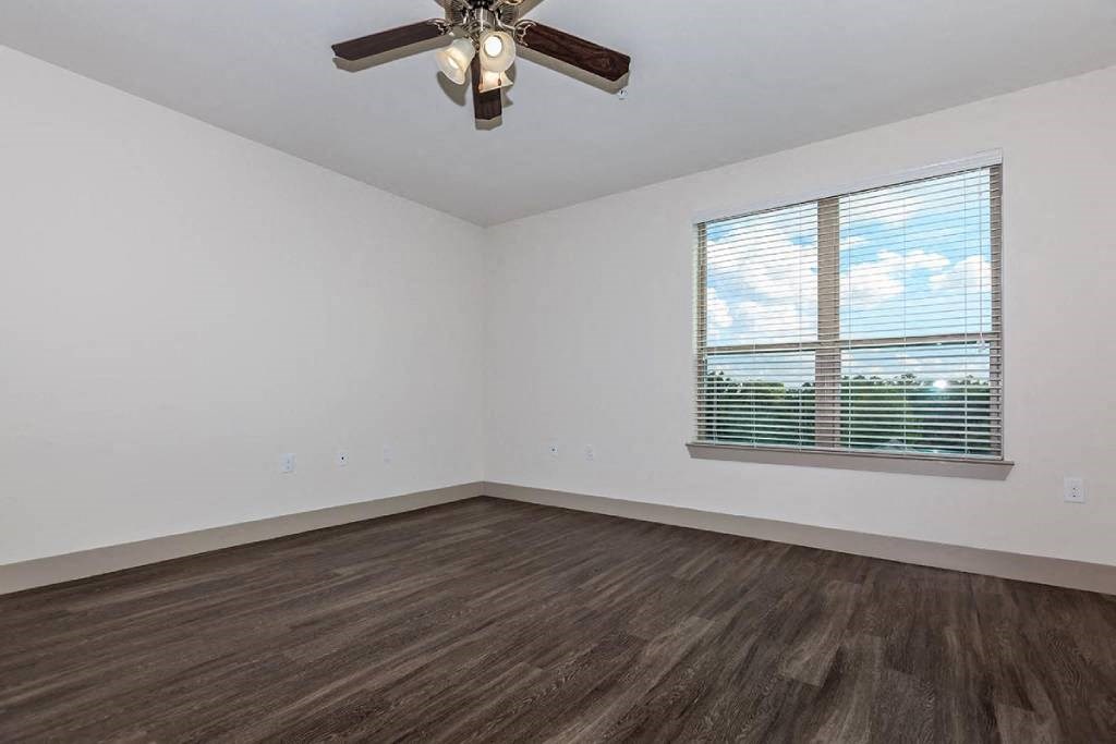 an empty room with a window and a ceiling fan