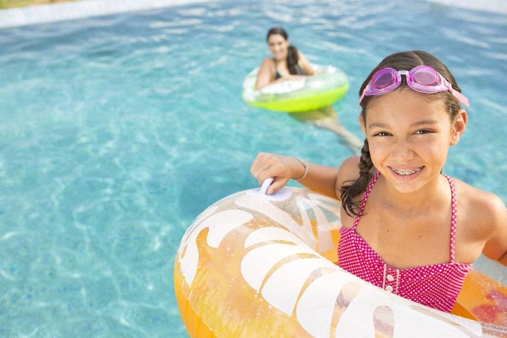 a young girl in a pool with a blow up ring