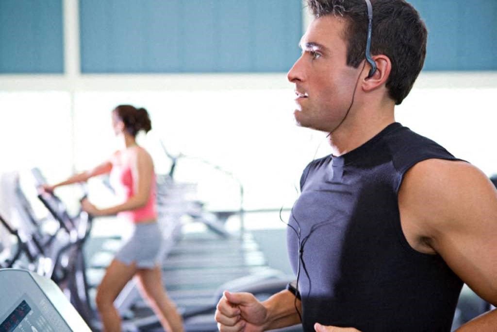 a man running on a treadmill at a gym while wearing headphones