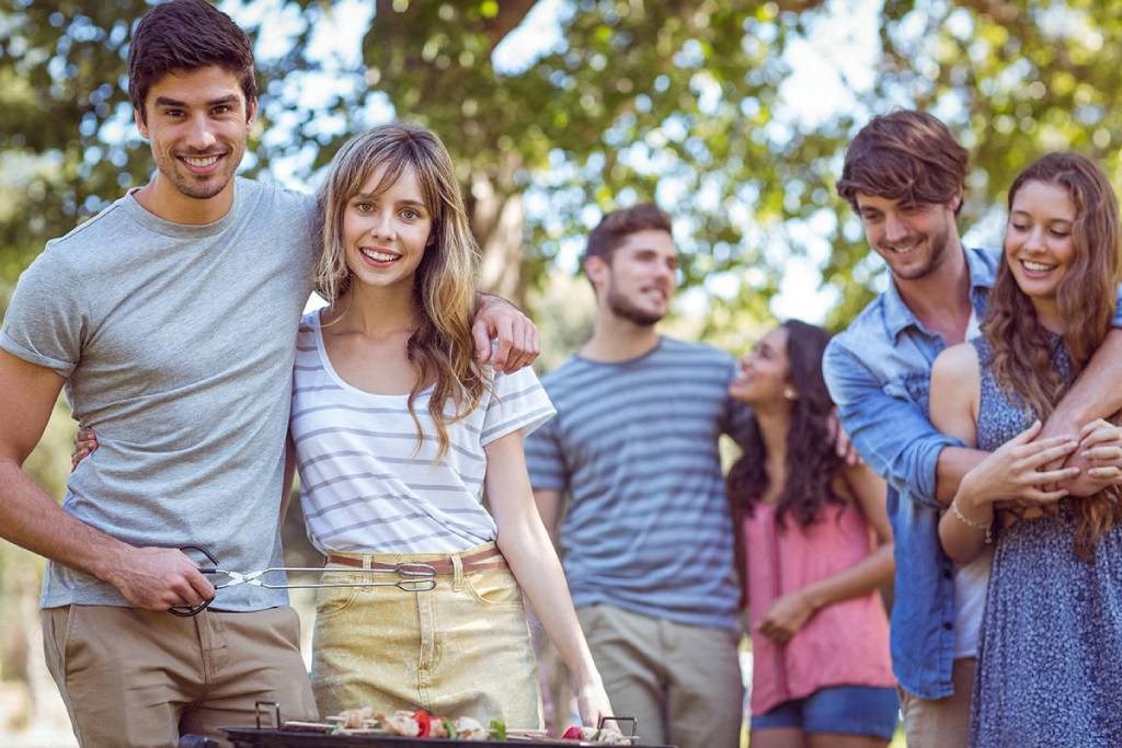 group of young people standing around a grill