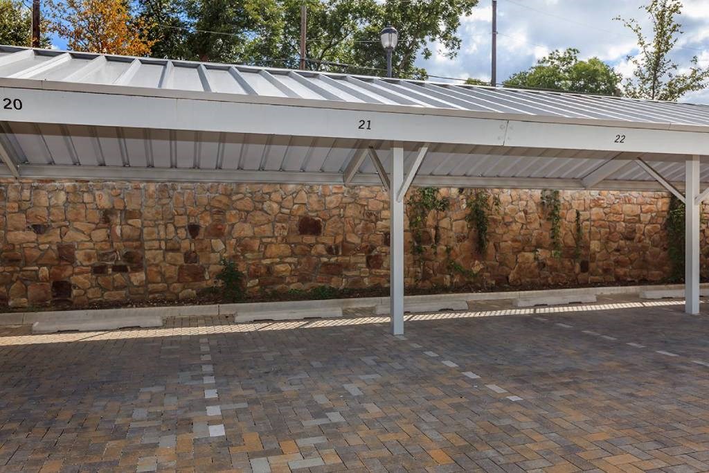 awning over a parking lot next to a stone wall