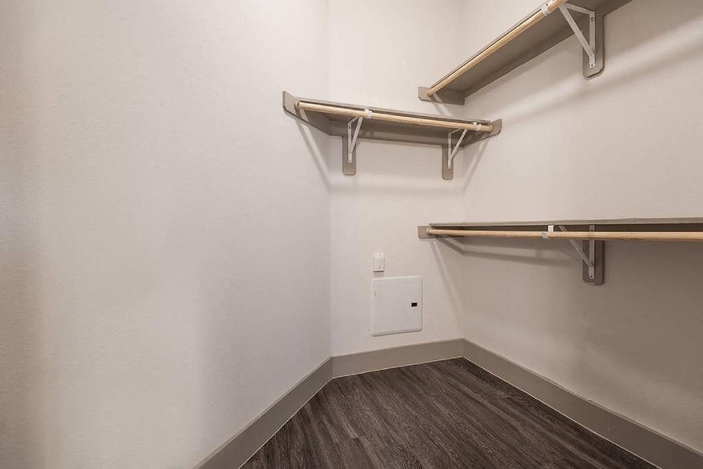 a empty room with a white wall and a white closet with shelves