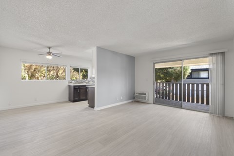 A spacious room with a ceiling fan and a view of a deck outside.