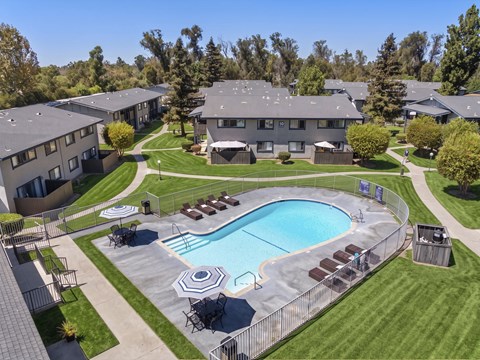 A swimming pool surrounded by a fence and chairs in a residential area.