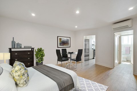 A bedroom with a bed, chair, and a painting on the wall.
