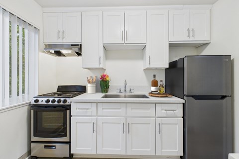 A kitchen with white cabinets and a black refrigerator.