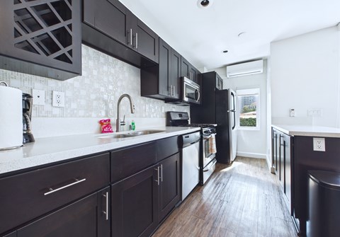 A kitchen with black cabinets and a white counter.