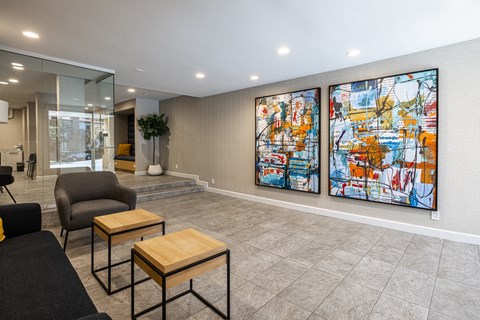 A living room with a grey sofa, a black chair, a wooden coffee table and two large paintings on the wall.