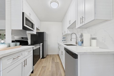 A kitchen with white cabinets and appliances.