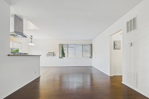 A spacious, empty room with wooden floors and white walls.