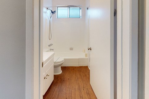 A white bathroom with a toilet, sink, and a window.