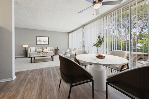 A living room with a white couch and a dining table with chairs.