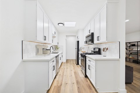 A modern kitchen with white cabinets and black appliances.