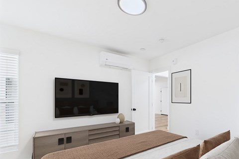 A modern bedroom with a large bed and a flat screen TV mounted on the wall.