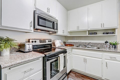 A white kitchen with a black stove top oven and microwave.