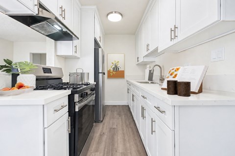 A kitchen with white cabinets and black appliances.