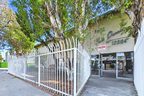 A white fence surrounds a building with a green sign that says Ques.