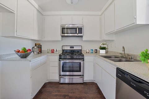 A modern kitchen with white cabinets and stainless steel appliances.