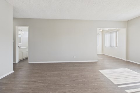 A spacious room with wooden flooring and white walls.
