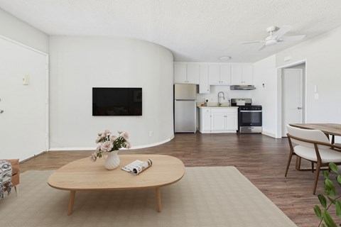 A living room with a wooden coffee table and a flat screen TV on the wall.