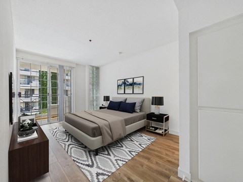A bedroom with a large bed and a balcony with a view of a building.